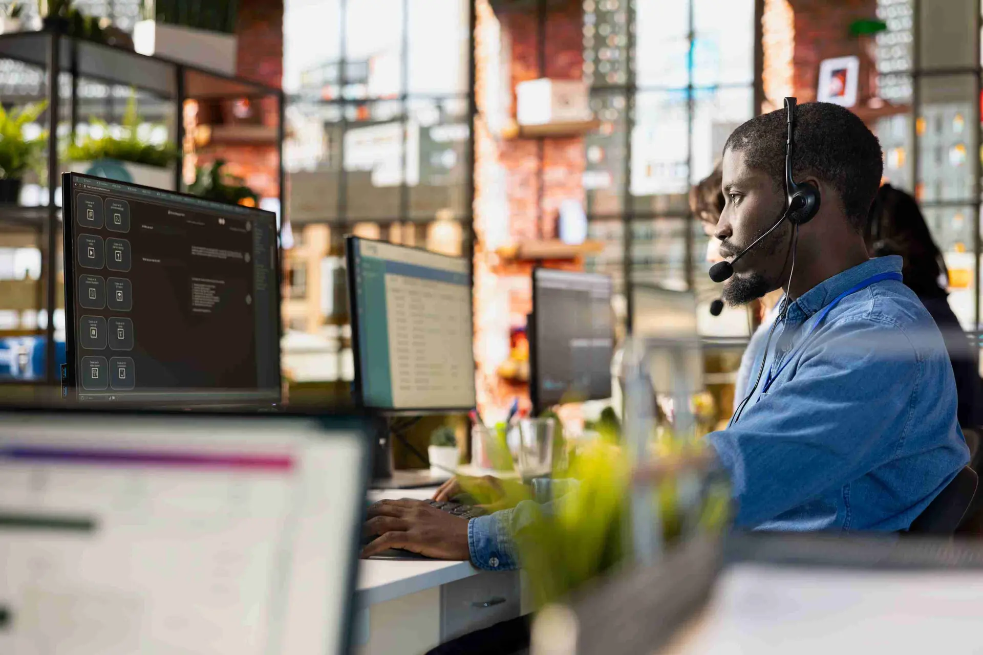 Contact center agent wearing headset working across multiple monitors, demonstrating omnichannel customer support tools within Dynamics 365 Contact Center | Dynamics Monk.
